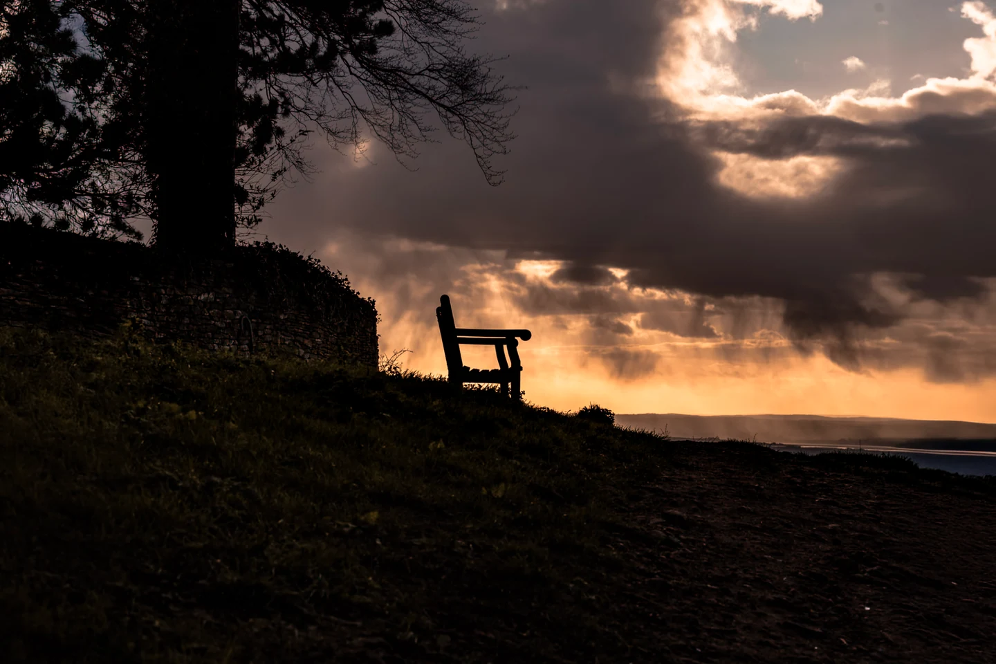 Bench by the coast beneath a dramatic evening sky