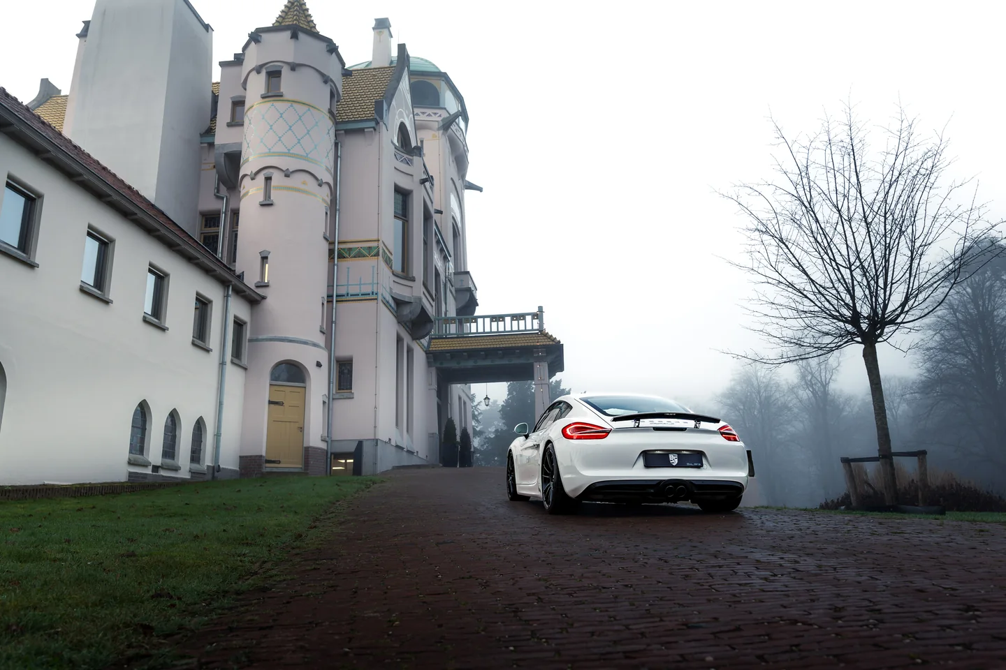 White Porsche beside a historic country house in fog